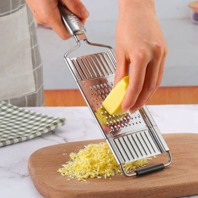 Personne utilisant une râpe à légumes manuelle inox interchangeal'ine pour râper du fromage