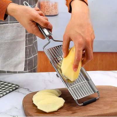 Personne utilisant une râpe à légumes manuelle inox interchangeal'ine pour trancher une pomme de terre.