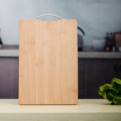 Planche à découper bois posé sur sa petite tranche, debout dans une cuisine.