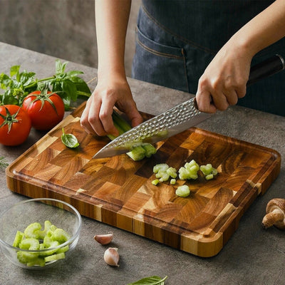 Planche à découper bois posée sur une table et utilisée par une personne pour couper des légumes avec un couteau.