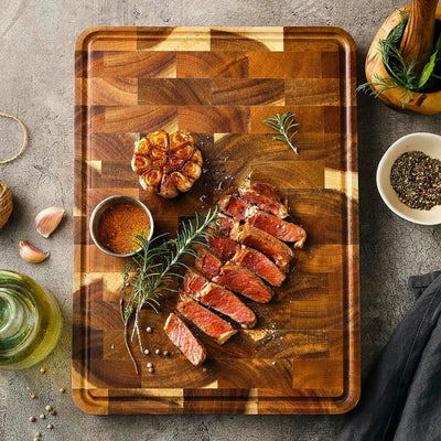 Planche à découper bois posée sur une table avec des morceaux de viande découpés joliment posés dessus.