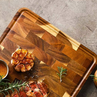 Planche à découper bois posée sur une table montrée sur une moitié avec des aliments dessus.