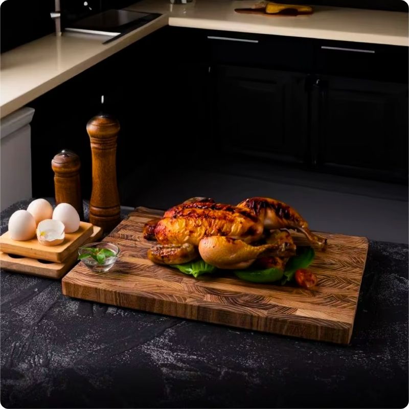 planche à découper bois teck massif avec un poulet posé dessus
