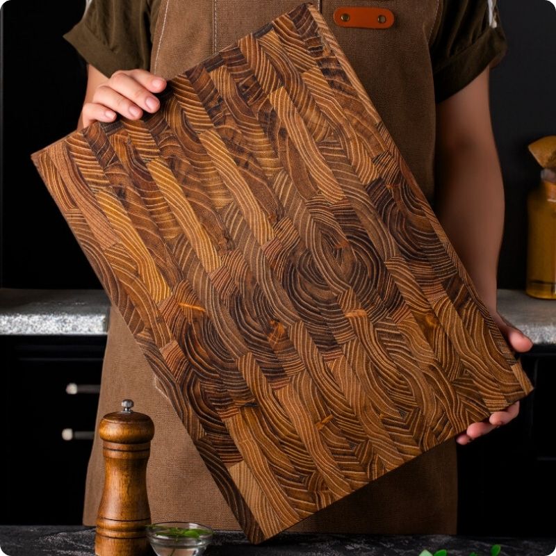 planche à découper bois teck massif tenue par une personne