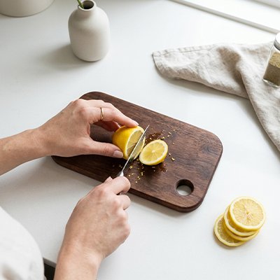 Planche à découper bois utilisée par une femme qui découpe des tranches de citron