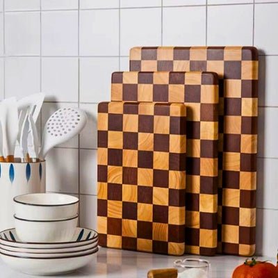 Planche à découper en bois en motif damier posé avec d'autres planches identiques de tailles différentes.