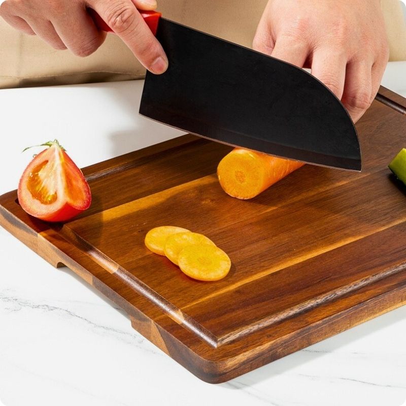 Planche à découper en bois utilisée pour couper un carotte