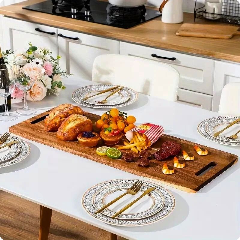 Planche à découper en bois XL acacia signature sur table à côté d'assiette.