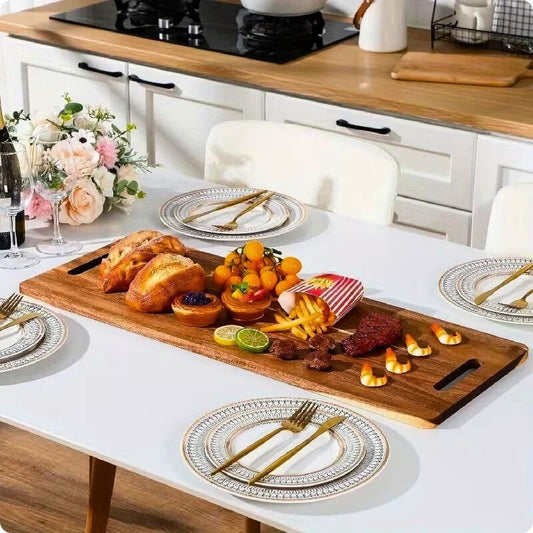 Planche à découper en bois XL acacia signature sur table à côté d'assiette.