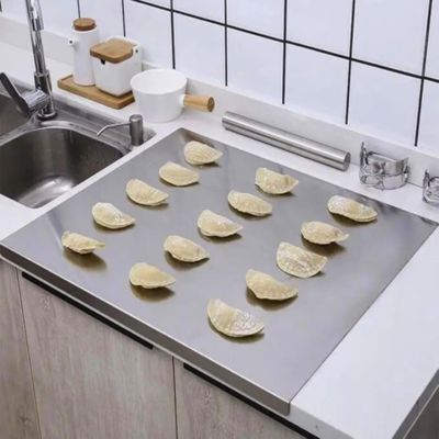 planche à découper en inox avec raviolli dessus