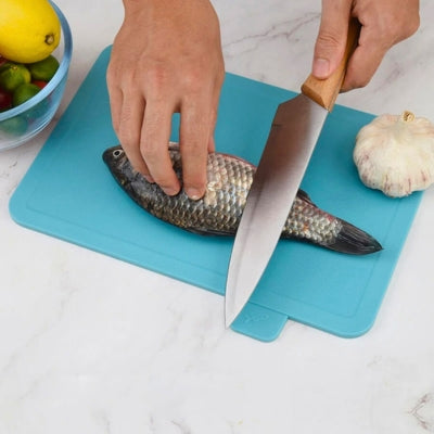 Planche a decouper de couleur bleue utilisée pour découper un poisson.