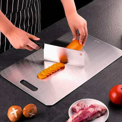 planche à découper inox utilisée par une personne pour couper une carotte.