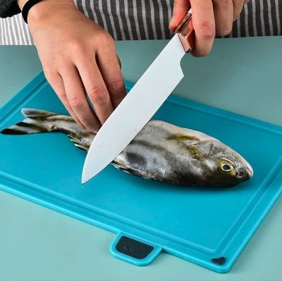 Personne coupant poisson sur planches à découper plastique