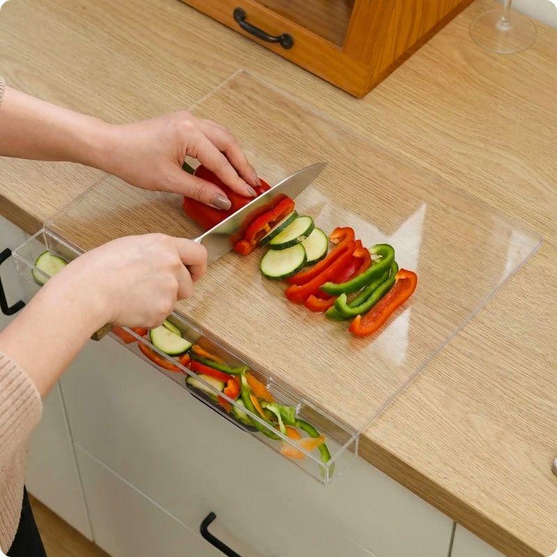 Planche à découper pour plan de travail glass'ine utilisée pour couper des poivrons et des courgettes
