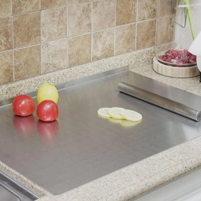 Planche a decouper posée sur plan de travail avec fruits et rouleau dessus.