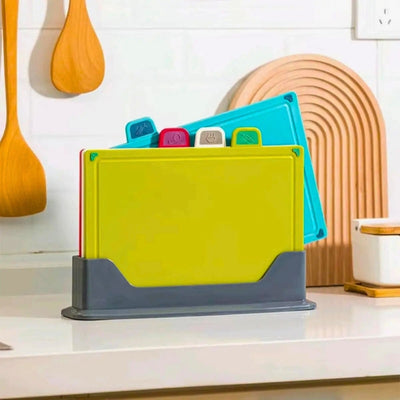 planches à découper plastique rangées dans un support de rangement posé sur une table, une planche de couleur bleue est légèrement sortie.
