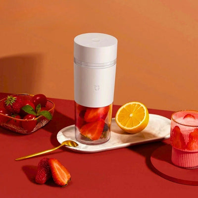Presse-agrume posé sur une table à côté de fruits et d'un smoothie.