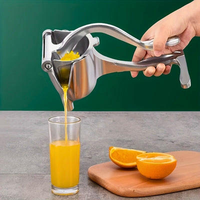 Presse agrume manuel tenu par une main d'une personne pour verser directement dans un verre du jus de fruit, en dessous une planche à découper avec des oranges coupées.