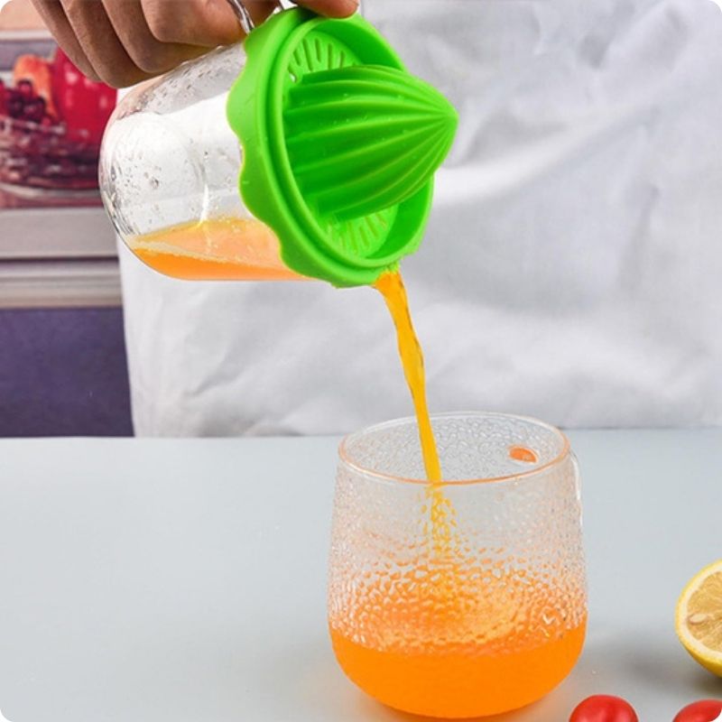 Jus d'orange pressé avec presse agrume manuel versé dans verre.