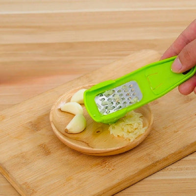 Presse ail utilisé par une personne qui pose le presse ail sur la coupelle qui est remplie d'ail pressé et de gousses d'ail.