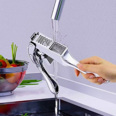 Presse ail tenu par une personne et qui le passe sous l'eau d'un robinet.