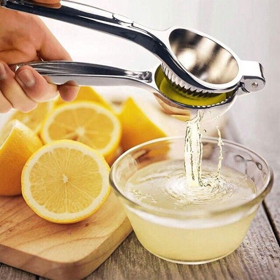Presse citron manuel dans les mains d'une personne qui réalise un jus de citron frais dans un plat