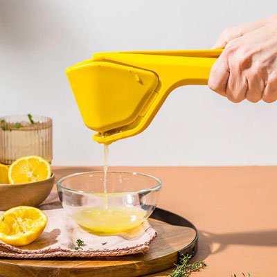 Presse citron manuel jaune utilisé pour presser un citron au dessus d'un bol