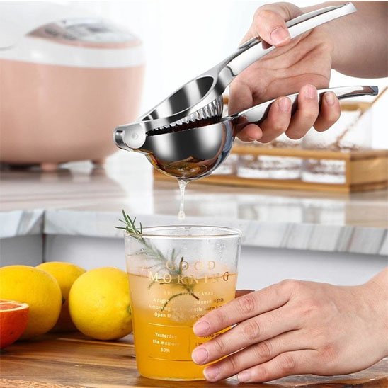 Presse citron manuel utilisé par un femme en cuisine qui prépare un jus frais