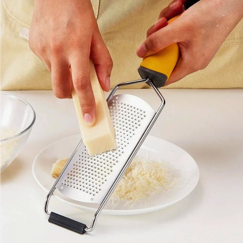 Râpe à fromage utilisée par une personne pour râper du fromage.