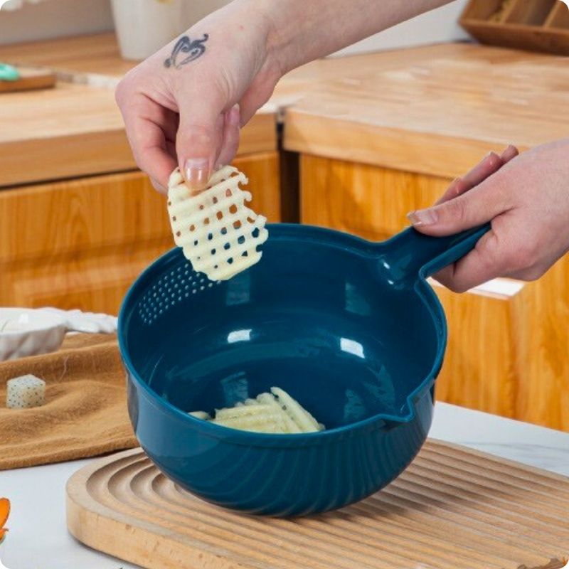 rape a legumes sur planche en bois avec une main qui tient une tranche de patate