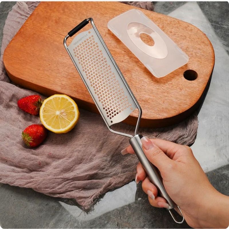 râpe manuelle tenue par une main au dessus d'une planche