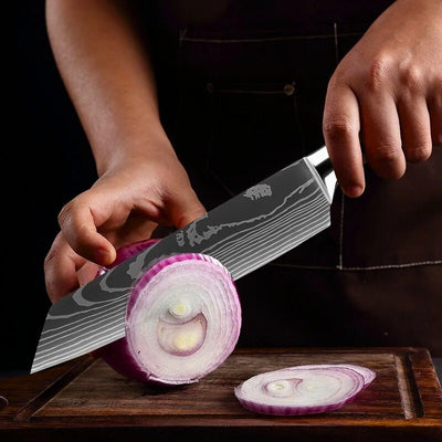 Personne en train de couper un oignon sur une planche à découper en bois avec un couteau de chef grande lame.