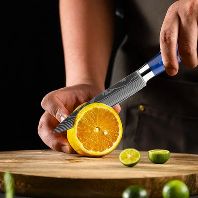 Personne en train de couper une orange sur une planche à découper en bois avec un couteau d'office grande lame.