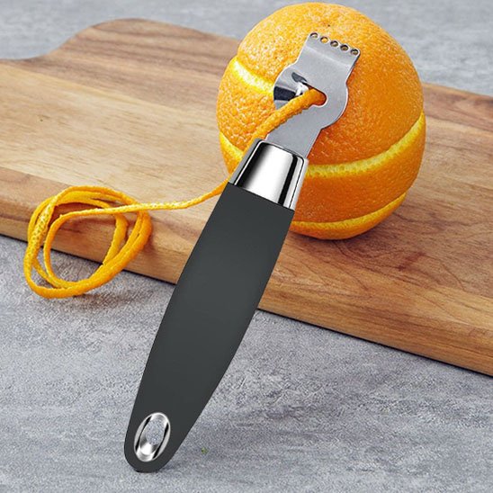 Zesteur posé sur une orange pelé en cuisine