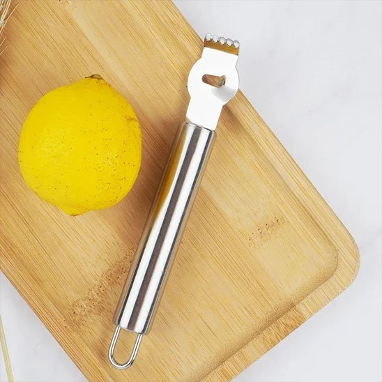 Zesteur posé sur une planche à découper avec un citron en présentation